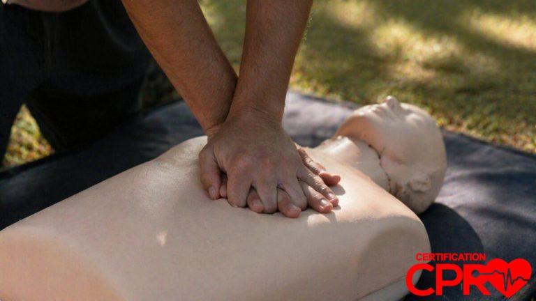 Person performing hands-only CPR on a mannequin outdoors in Atlanta.